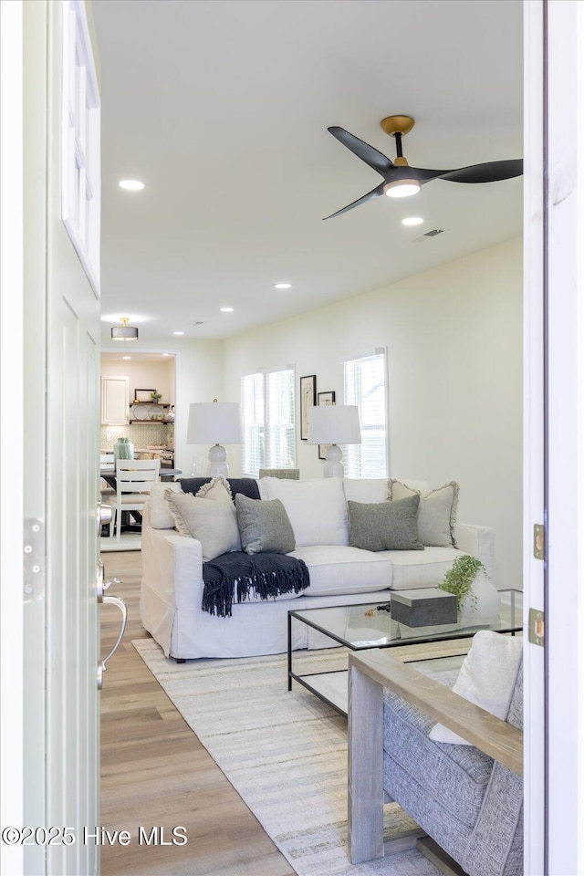 living room with light hardwood / wood-style floors and ceiling fan