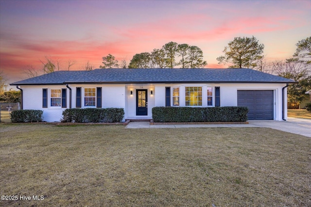 ranch-style home featuring a garage and a lawn