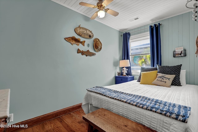 bedroom with wooden ceiling, wooden walls, ceiling fan, ornamental molding, and wood-type flooring