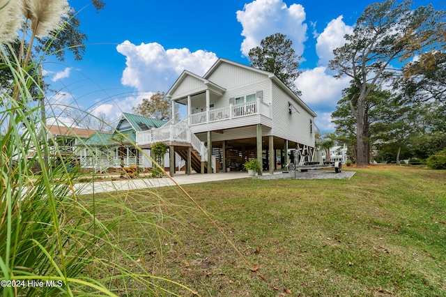 raised beach house with covered porch, a front lawn, and a carport