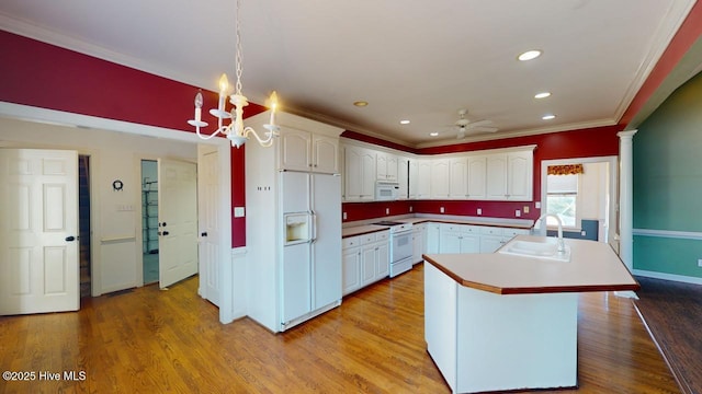 kitchen featuring white appliances, sink, light hardwood / wood-style flooring, white cabinets, and a kitchen island