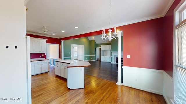 kitchen with white cabinets, a kitchen island, decorative light fixtures, and light wood-type flooring