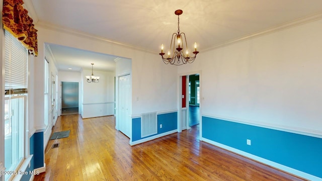 unfurnished room with crown molding, light hardwood / wood-style floors, and a notable chandelier