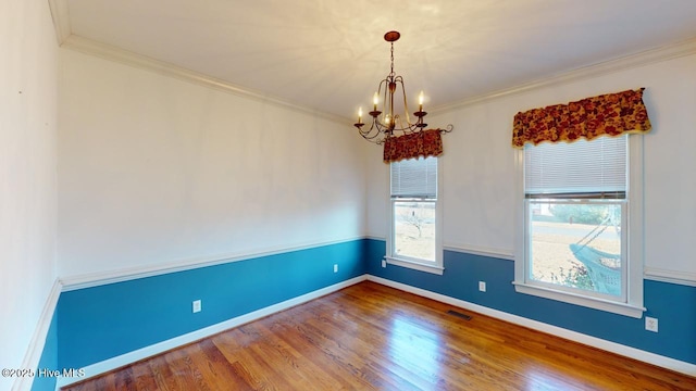 empty room with ornamental molding, wood-type flooring, and an inviting chandelier