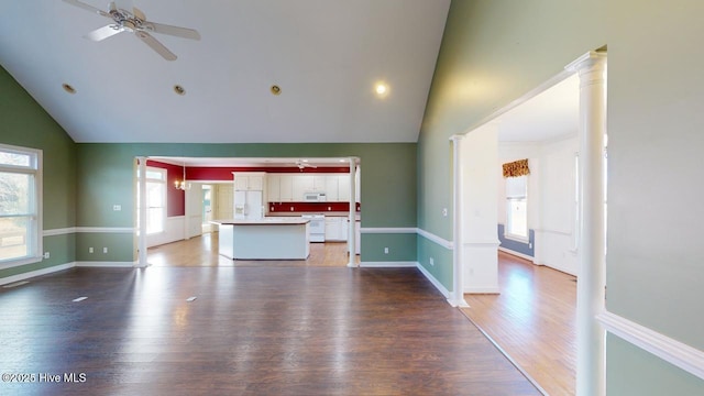 unfurnished living room with ornate columns, ceiling fan, hardwood / wood-style floors, and lofted ceiling