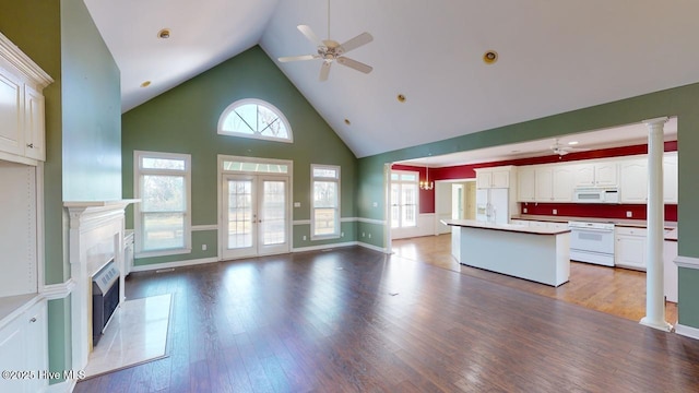 kitchen featuring hardwood / wood-style floors, white appliances, a tile fireplace, a kitchen island, and white cabinetry