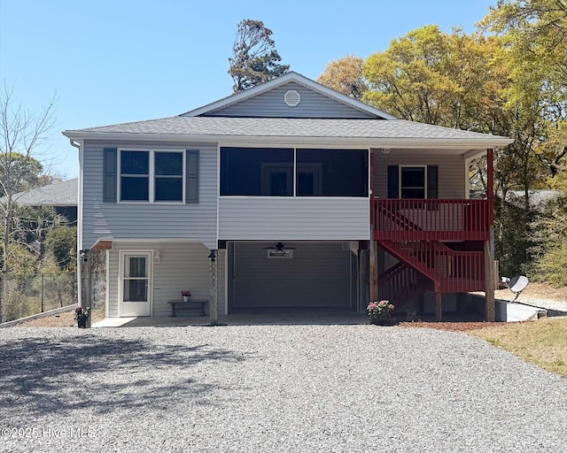 coastal home with a carport, stairway, driveway, and roof with shingles