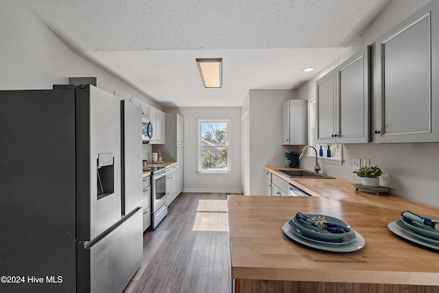 kitchen featuring sink, stainless steel appliances, dark hardwood / wood-style flooring, wooden counters, and a textured ceiling