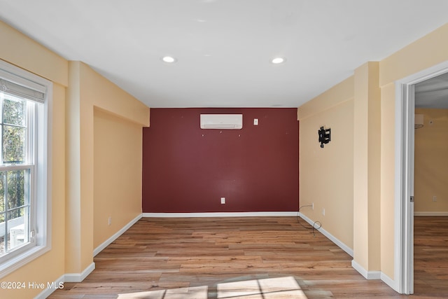spare room featuring wood finished floors, a wall mounted air conditioner, baseboards, and recessed lighting