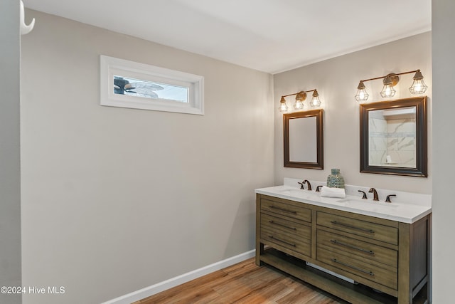 full bath with a sink, baseboards, double vanity, and wood finished floors