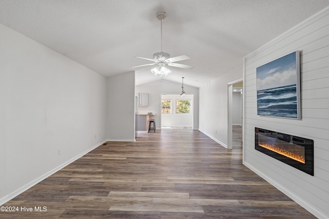 unfurnished living room with ceiling fan, a textured ceiling, a fireplace, dark wood-type flooring, and lofted ceiling