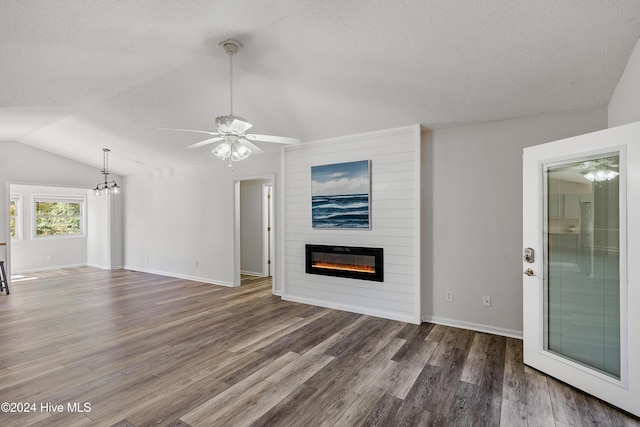 unfurnished living room with a large fireplace, a textured ceiling, lofted ceiling, ceiling fan with notable chandelier, and wood finished floors