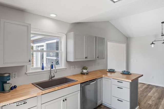 kitchen featuring a sink, a peninsula, butcher block countertops, stainless steel dishwasher, and lofted ceiling