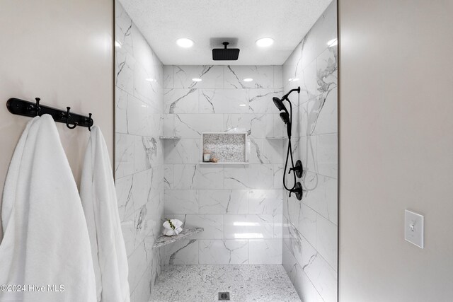 bathroom featuring a tile shower and a textured ceiling