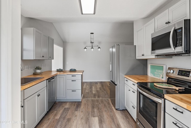 kitchen featuring a sink, dark wood-style floors, vaulted ceiling, stainless steel appliances, and butcher block countertops