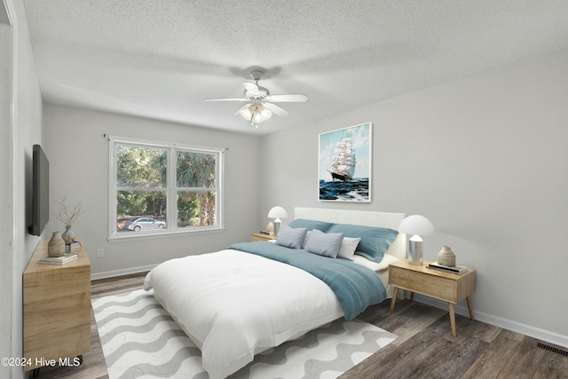 bedroom with ceiling fan, wood-type flooring, and a textured ceiling