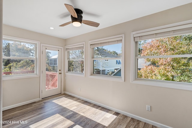 unfurnished sunroom with wood finished floors, baseboards, and recessed lighting