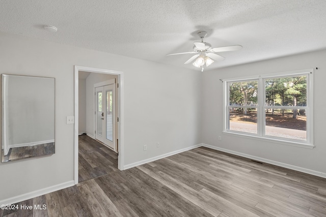 spare room featuring ceiling fan, plenty of natural light, wood finished floors, and a textured ceiling