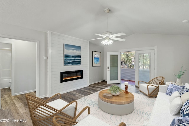 living room featuring vaulted ceiling, a large fireplace, baseboards, and wood finished floors