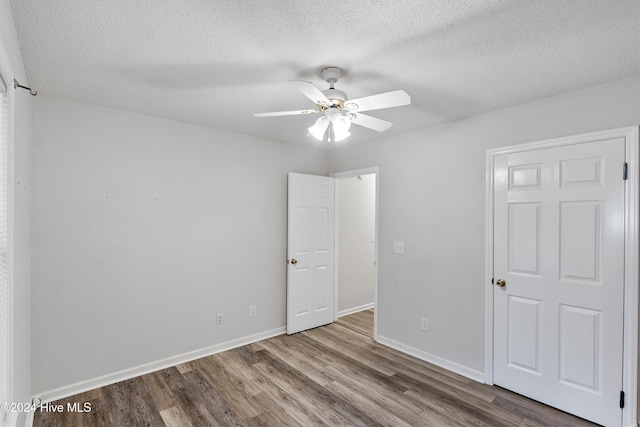 unfurnished bedroom with a textured ceiling, baseboards, a ceiling fan, and wood finished floors