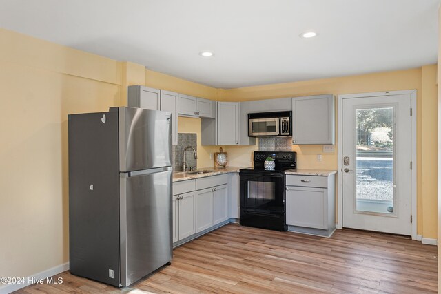 kitchen featuring appliances with stainless steel finishes, light wood-type flooring, gray cabinets, and sink