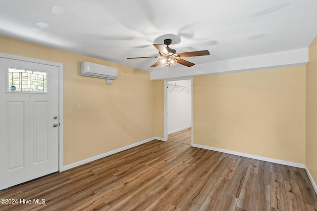 entrance foyer with a wall mounted AC, light wood-style flooring, baseboards, and a ceiling fan