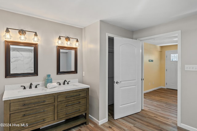 full bath with a sink, baseboards, and wood finished floors