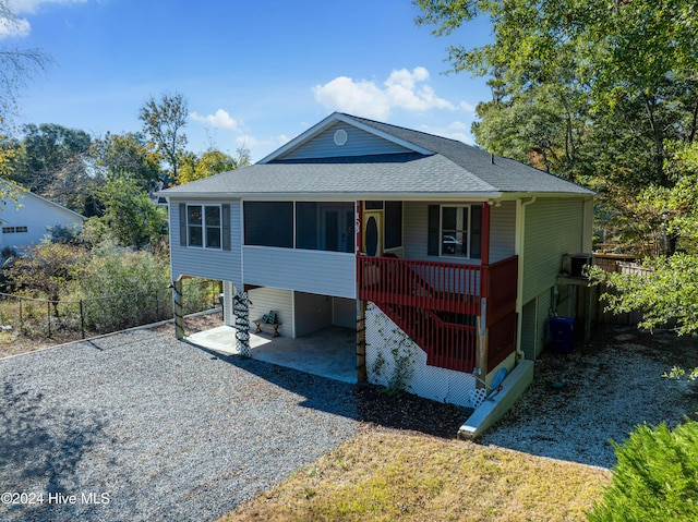 view of front of house with a sunroom, a carport, fence, a shingled roof, and driveway