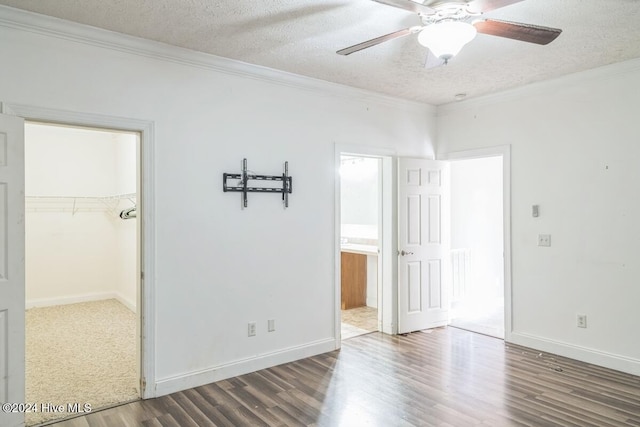 empty room featuring a textured ceiling, dark hardwood / wood-style floors, ceiling fan, and crown molding