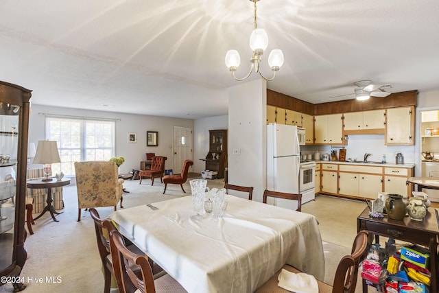 carpeted dining space with ceiling fan with notable chandelier and sink