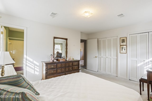 carpeted bedroom with a textured ceiling and two closets