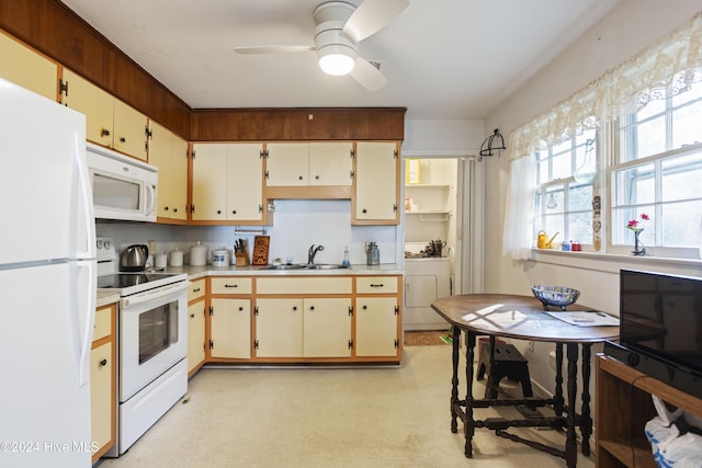 kitchen with white appliances, sink, ceiling fan, cream cabinetry, and washer / clothes dryer