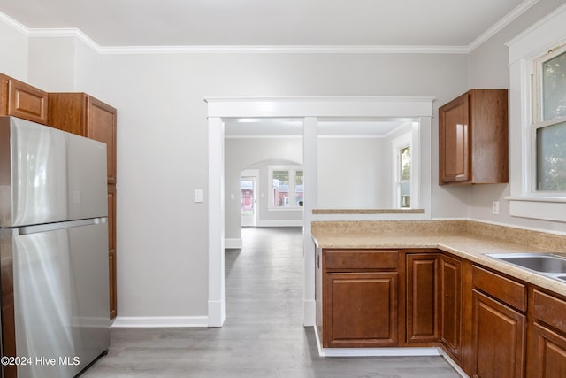 kitchen featuring stainless steel fridge, crown molding, light hardwood / wood-style floors, and sink