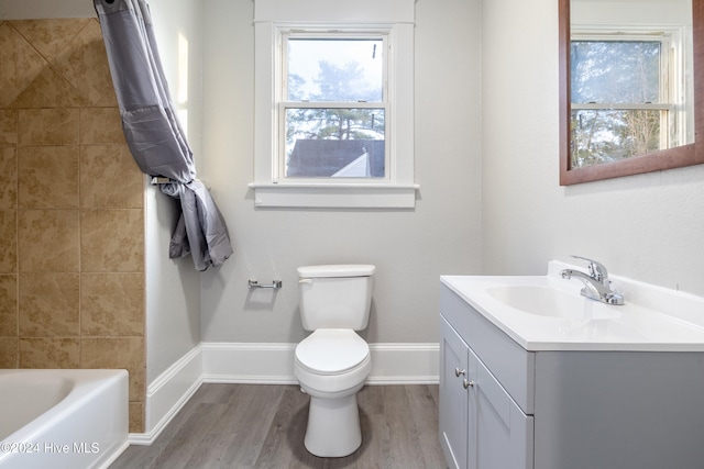 full bathroom with hardwood / wood-style floors, vanity, shower / tub combo, and toilet