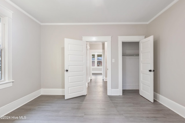 unfurnished bedroom with light hardwood / wood-style floors, a closet, and crown molding