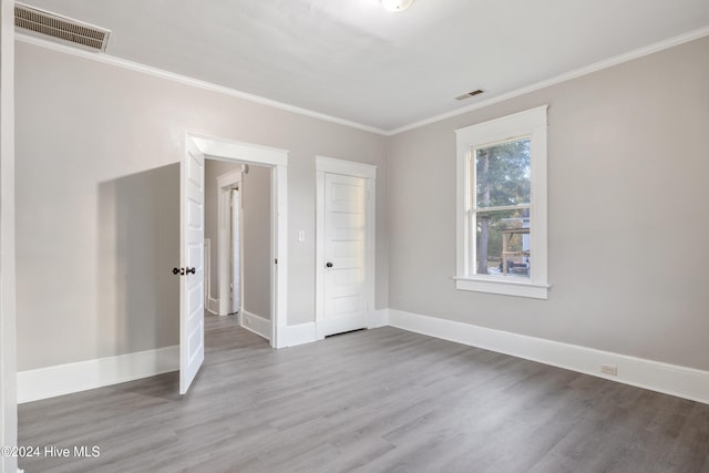 unfurnished bedroom featuring wood-type flooring, crown molding, and a closet