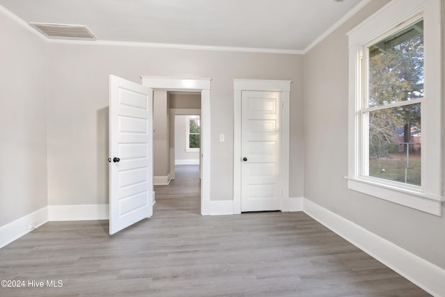 spare room with light hardwood / wood-style floors and crown molding