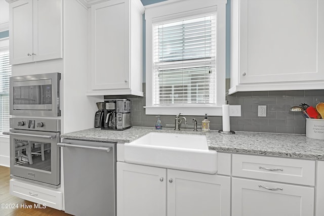 kitchen featuring hardwood / wood-style floors, white cabinets, sink, tasteful backsplash, and stainless steel appliances