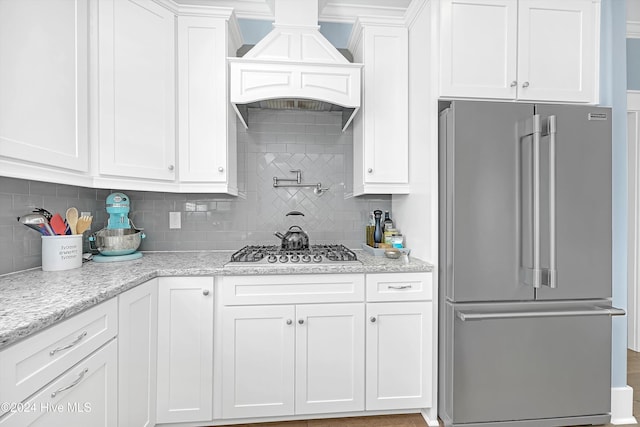 kitchen featuring white cabinets, appliances with stainless steel finishes, backsplash, and light stone counters