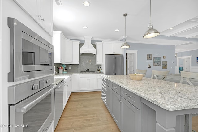 kitchen with custom exhaust hood, light hardwood / wood-style flooring, appliances with stainless steel finishes, a kitchen island, and white cabinetry