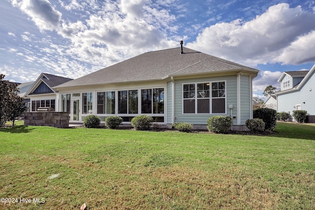 rear view of property with a lawn and a sunroom