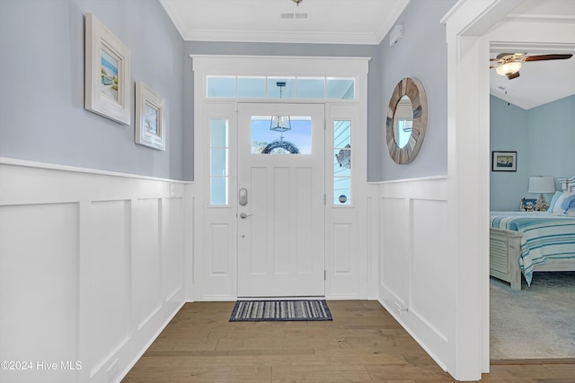 entrance foyer featuring wood-type flooring, ceiling fan, and crown molding