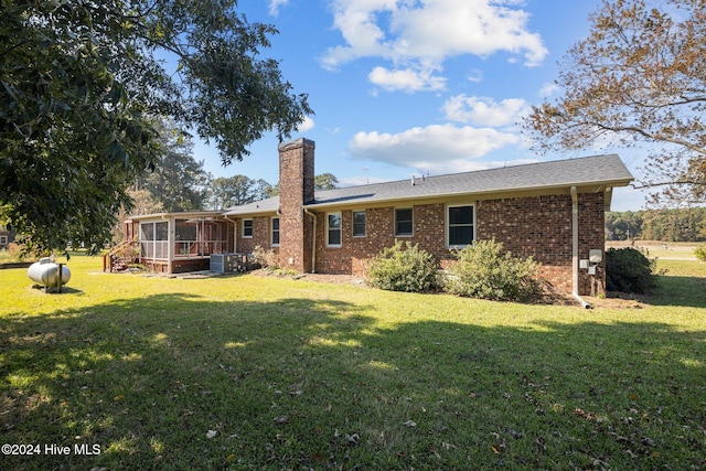 back of property featuring a sunroom, central AC unit, and a lawn