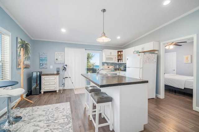 kitchen with white appliances, dark wood-type flooring, white cabinets, vaulted ceiling, and tasteful backsplash