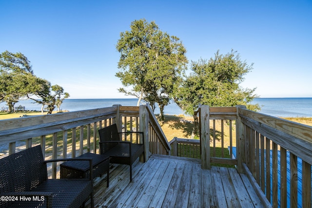 wooden deck featuring a beach view and a water view