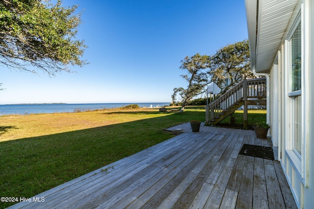 wooden deck featuring a lawn and a water view