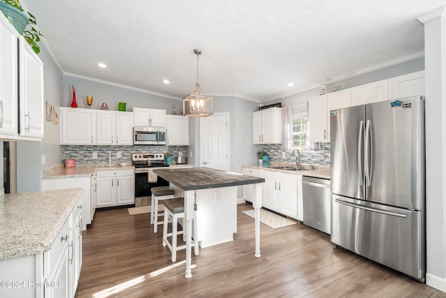 kitchen with dark wood-type flooring, wooden counters, appliances with stainless steel finishes, a kitchen island, and white cabinetry