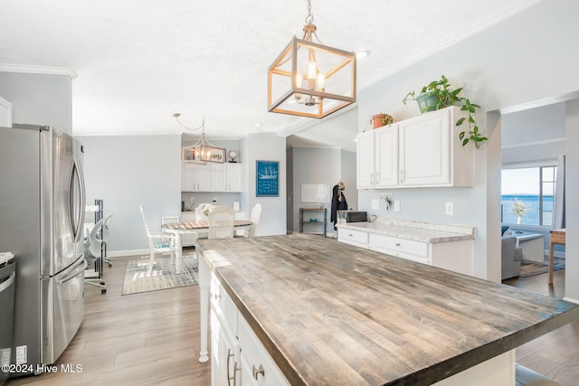 kitchen featuring white cabinets, appliances with stainless steel finishes, butcher block countertops, and pendant lighting