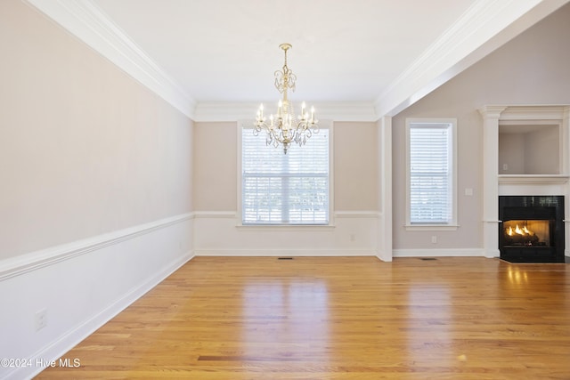 unfurnished dining area featuring light hardwood / wood-style floors, ornamental molding, and a chandelier