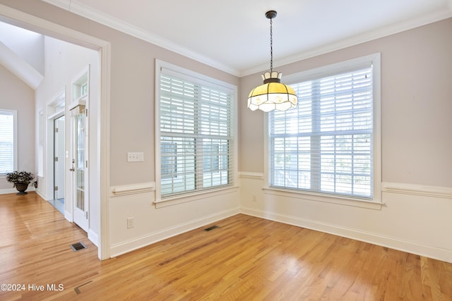 unfurnished dining area with hardwood / wood-style floors, a wealth of natural light, and crown molding